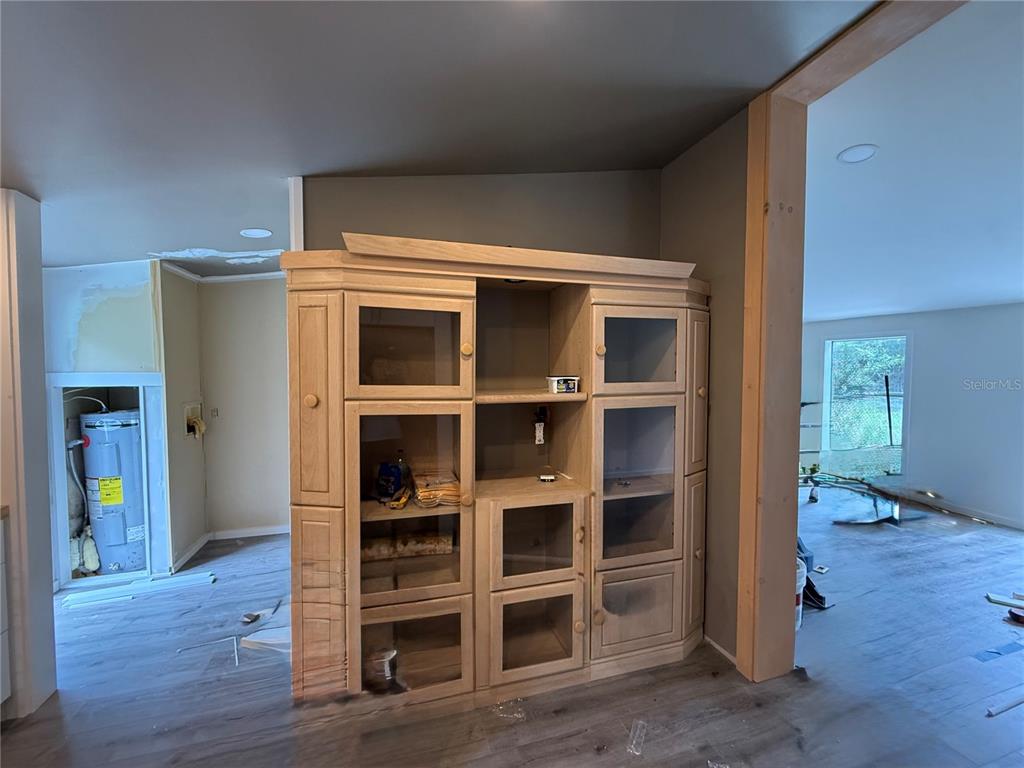 A large wooden entertainment center stands in a room with light wood-look flooring — 11091 NE 107TH TERRACE, ARCHER, FL