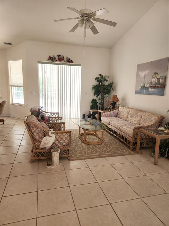 A living room features tile flooring, a ceiling fan, wicker furniture, and a sliding glass door — 10365 PALMWOOD PLACE, WEEKI WACHEE, FL