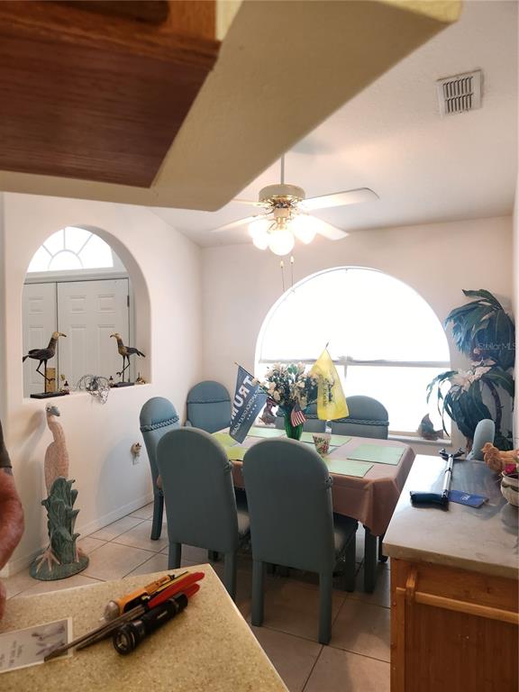 A dining area features blue chairs, a table with flags, and arched windows — 10365 PALMWOOD PLACE, WEEKI WACHEE, FL