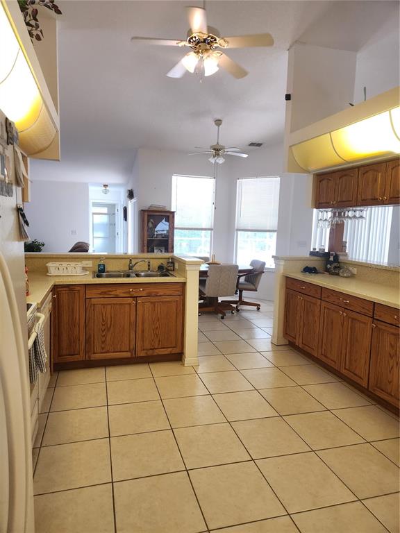 A kitchen with oak cabinets, tile flooring, and a breakfast area with a ceiling fan — 10365 PALMWOOD PLACE, WEEKI WACHEE, FL