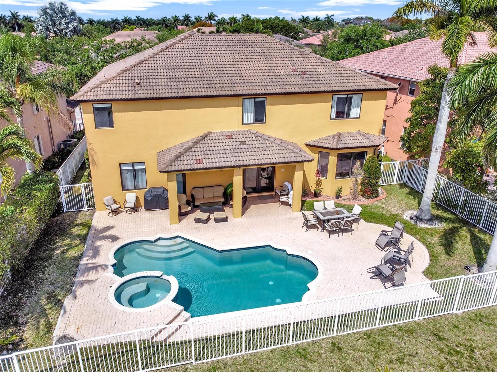 An aerial view of a two-story yellow house with a pool, spa, and patio — 3872 W Hibiscus Street, Weston FL 33332, WESTON, FL