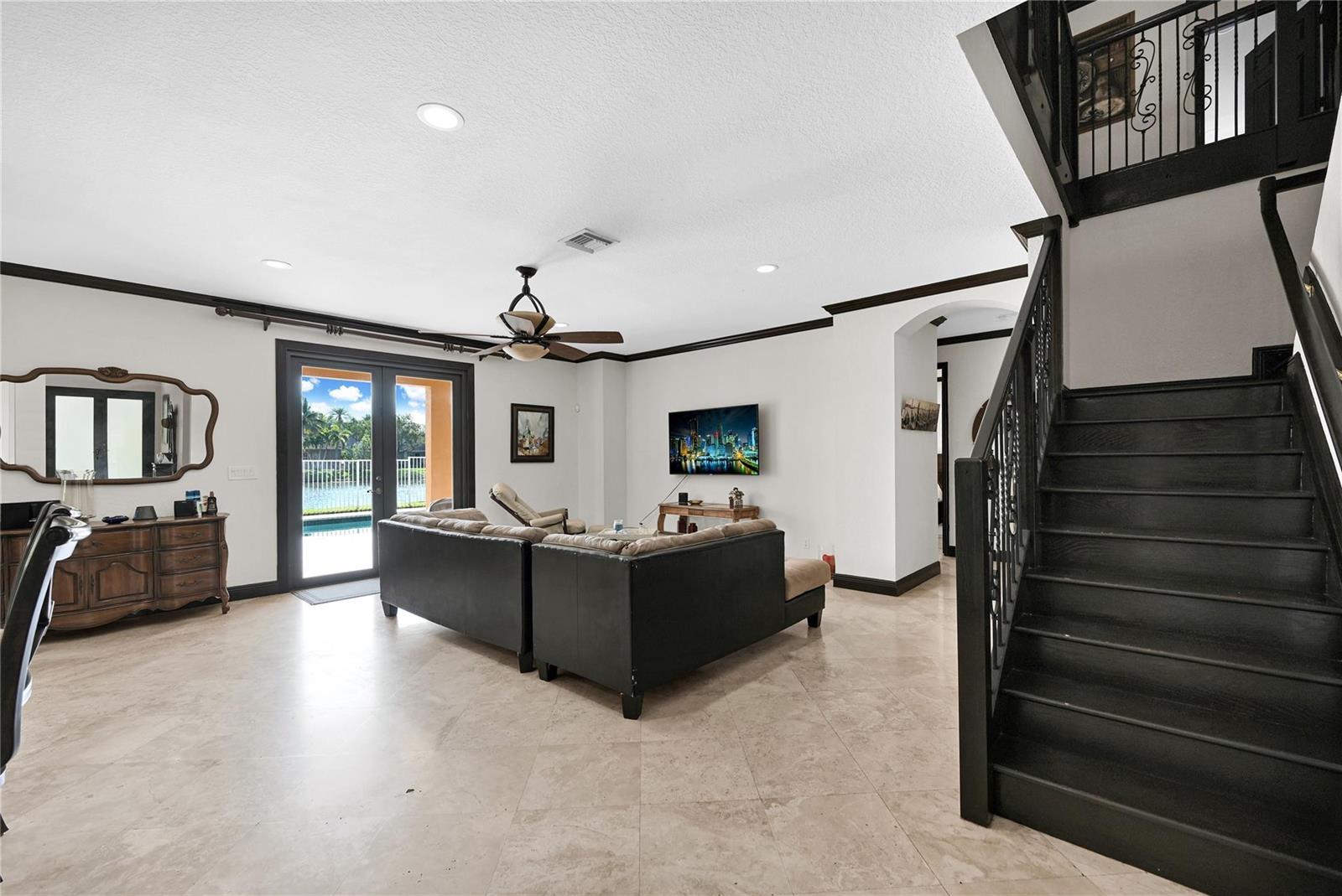 A living room features tile floors, a black staircase, and glass doors overlooking a pool — 3872 W Hibiscus Street, Weston FL 33332, WESTON, FL