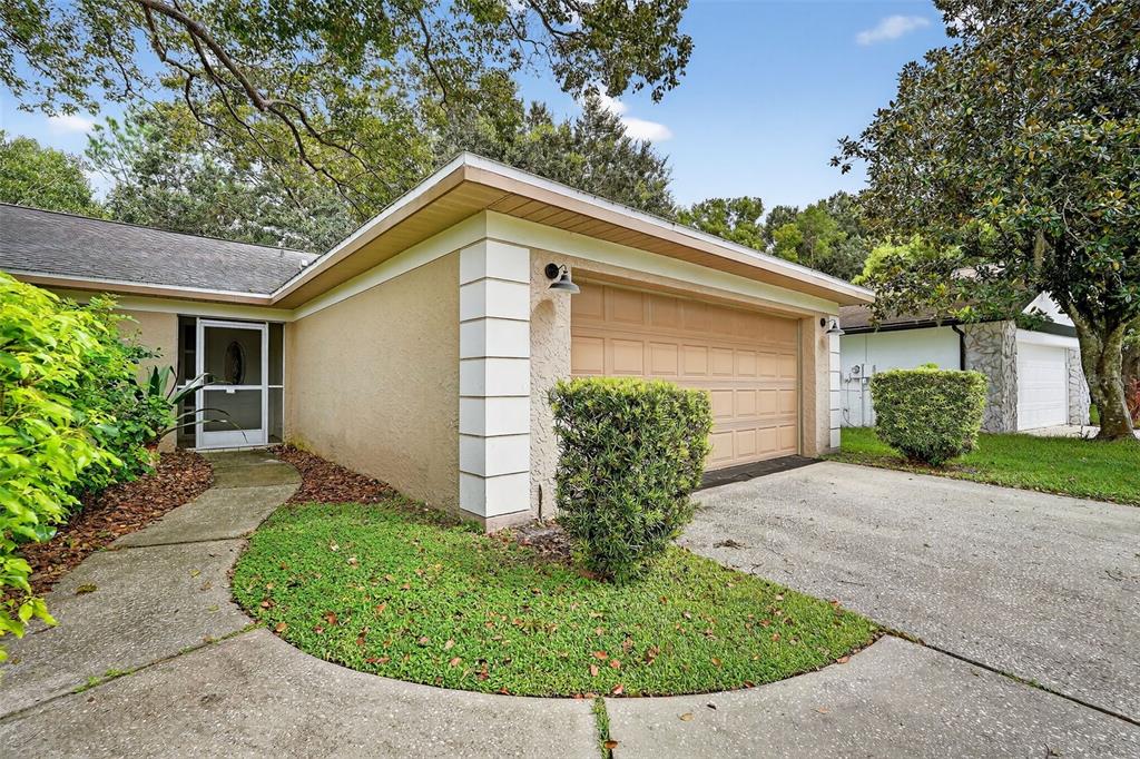 A beige house exterior features a single-car garage, a front walkway, and manicured landscaping — 3602 PLAYER DRIVE, NEW PORT RICHEY, FL
