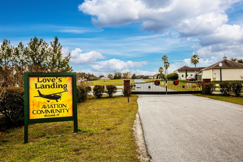 A sign for Love's Landing aviation community stands beside a gated entrance to a neighborhood — 17520 SE 159TH TERRACE, WEIRSDALE, FL