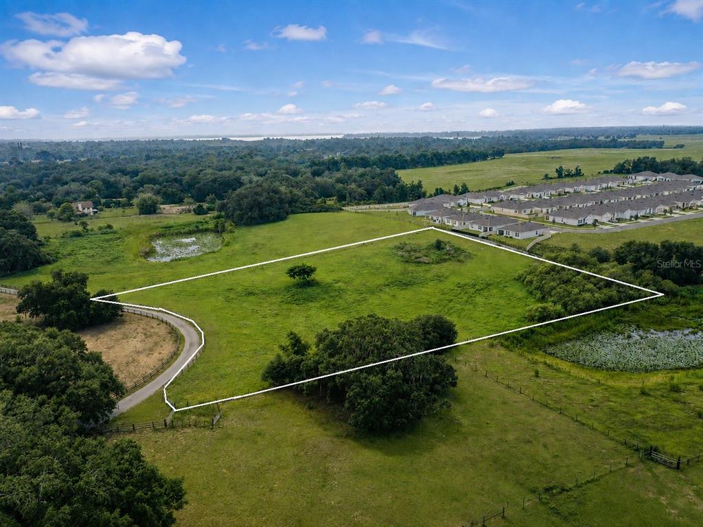 An aerial view shows a large, grassy vacant lot outlined in white near a residential neighborhood — 0 E HINSON AVENUE E, HAINES CITY, FL