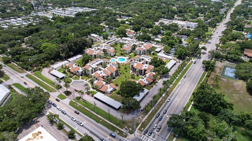 An aerial view shows a multi-building apartment complex with a central swimming pool and parking — 2207 BELLEAIR ROAD UNIT B16, CLEARWATER, FL