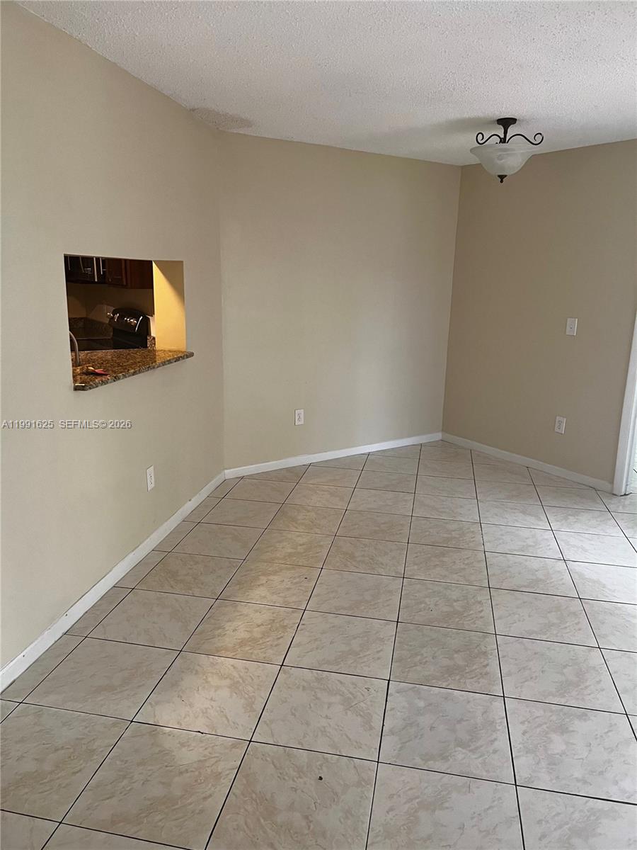 This room features beige walls, light-colored tile flooring, and a kitchen pass-through window — 802 Constitution Dr # 802B, Homestead FL 33034, HOMESTEAD, FL