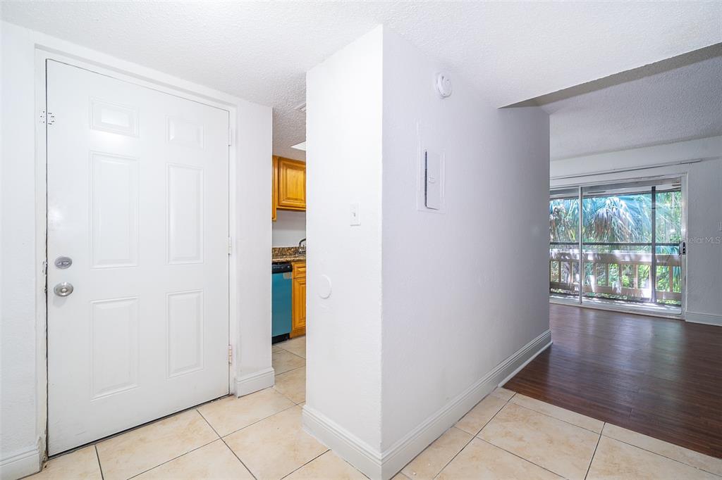 An entryway with tile flooring leads to a kitchen and a living area with wood floors — 4779 S TEXAS AVENUE UNIT 4779D, ORLANDO, FL
