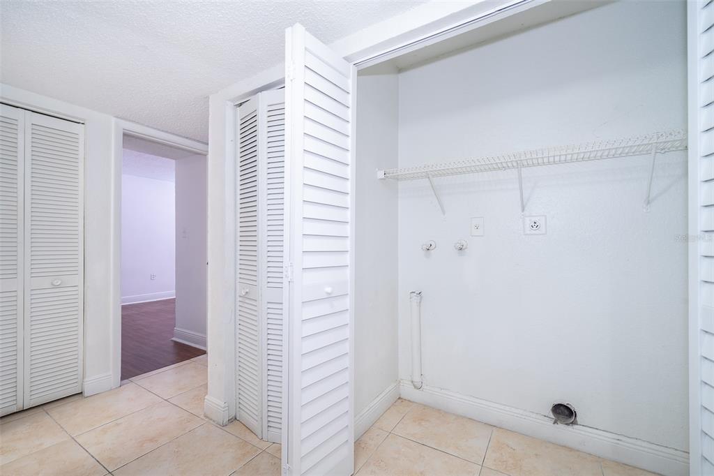 A laundry closet with white louvered doors, a wire shelf, and utility hookups on tile floors — 4779 S TEXAS AVENUE UNIT 4779D, ORLANDO, FL