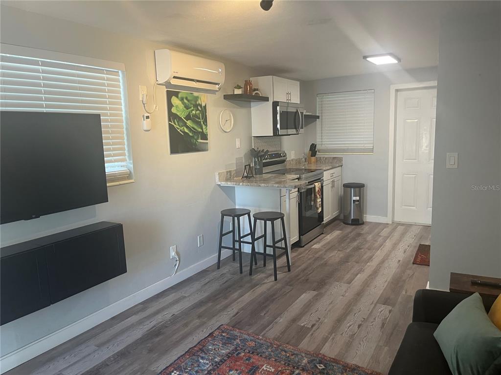This open-concept kitchen and living area features light wood-look flooring and a breakfast bar — 115 CLEVELAND AVENUE, LARGO, FL