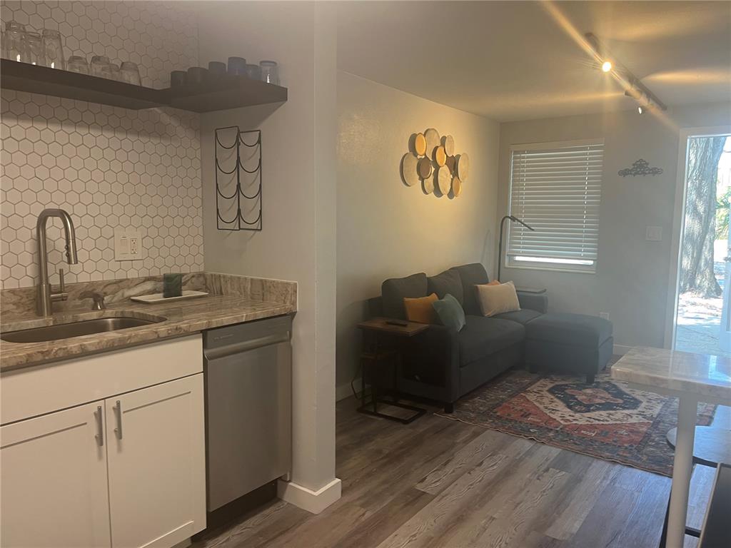 A kitchen with white cabinets and a tiled backsplash opens into a living room area — 115 CLEVELAND AVENUE, LARGO, FL