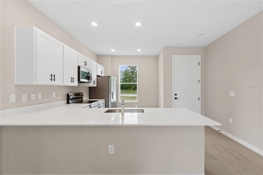 A modern kitchen features white cabinets, stainless steel appliances, and a white quartz island countertop — 2910 SW 165 STREET ROAD, OCALA, FL
