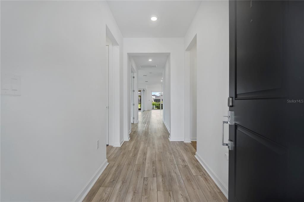 A bright hallway with light wood-look flooring leads toward an open living area — 42530 ATLAS DRIVE, PUNTA GORDA, FL