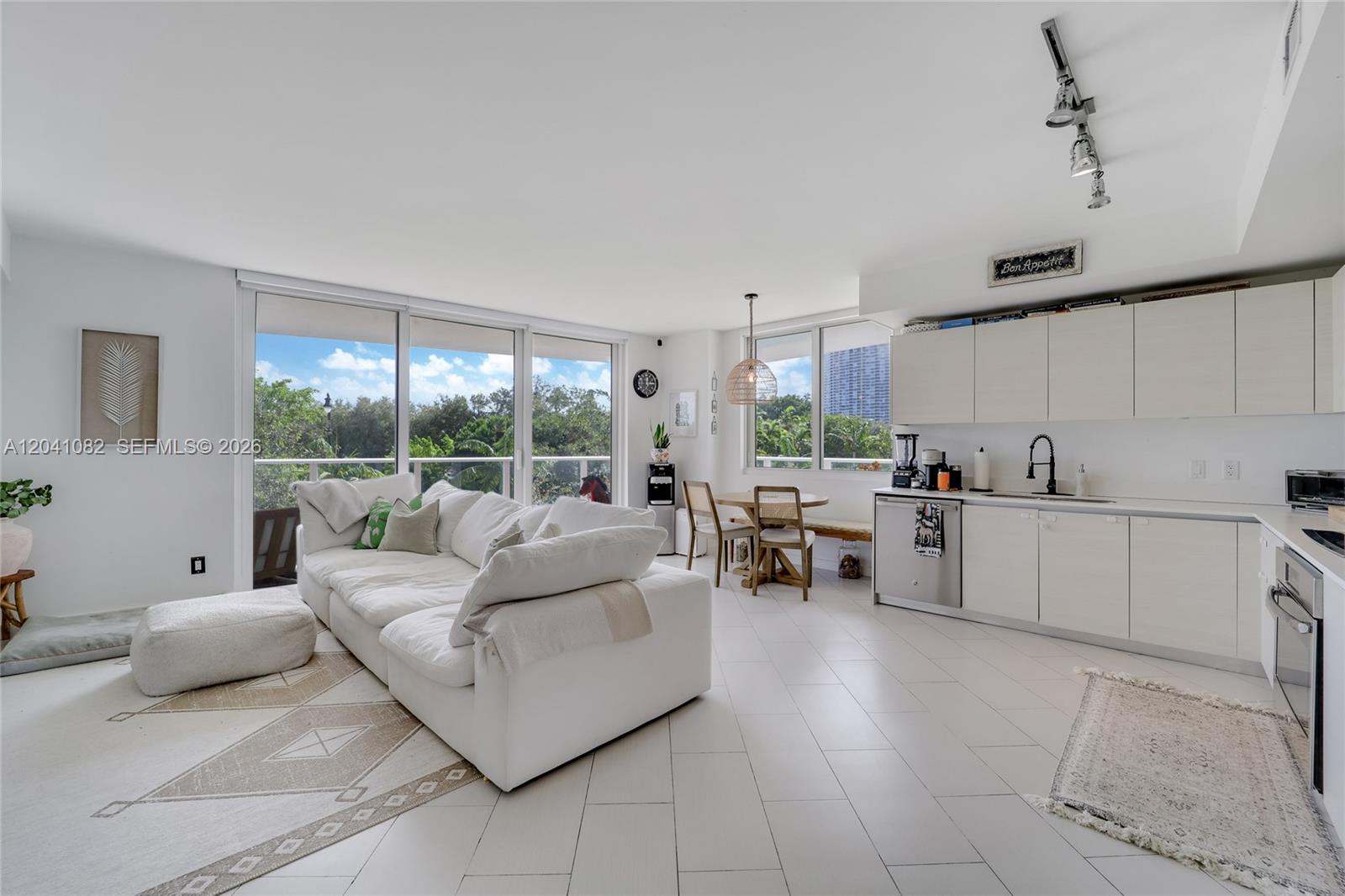 A bright, open-concept living area features a white sofa, dining nook, and modern kitchen — 4250 Biscayne Blvd # 301, Miami FL 33137, MIAMI, FL