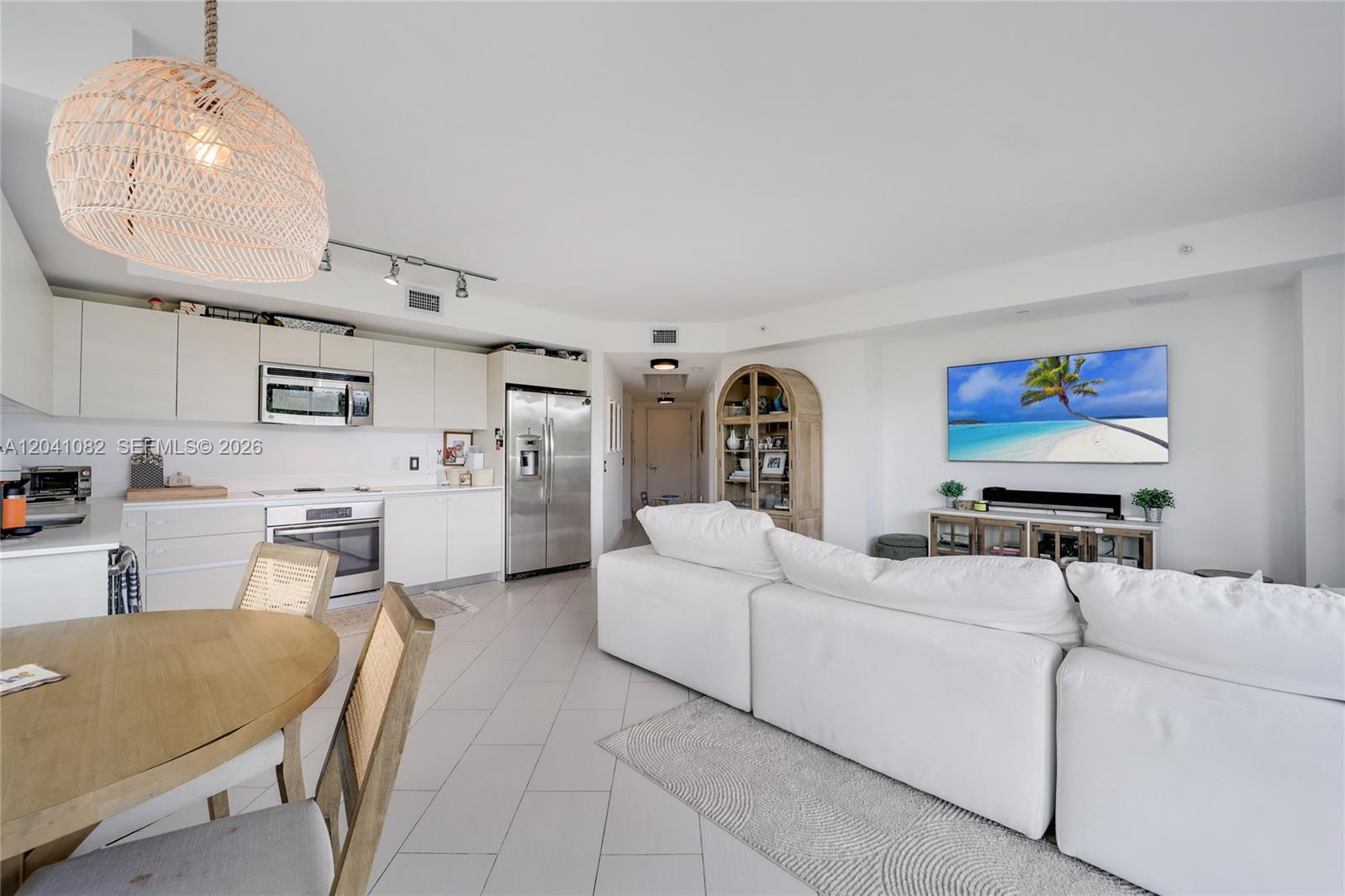 An open-concept living area features a white kitchen, dining table, and a large sectional sofa — 4250 Biscayne Blvd # 301, Miami FL 33137, MIAMI, FL