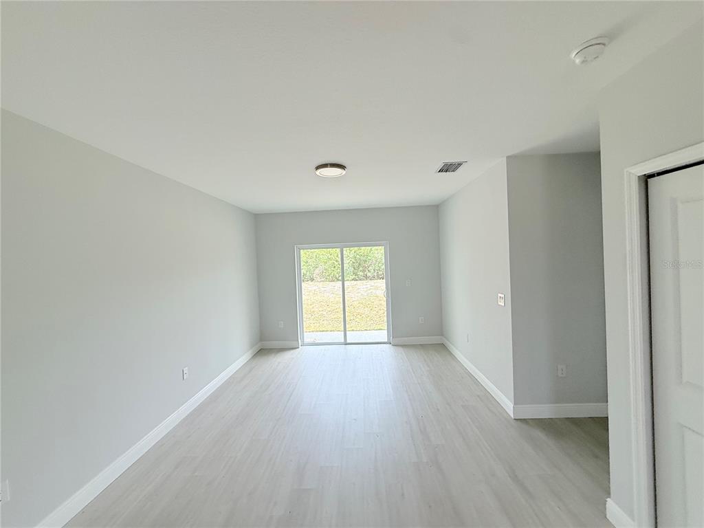 An empty room with light gray walls, wood-look flooring, and a sliding glass door — 11225 PENDLETON AVENUE, ENGLEWOOD, FL