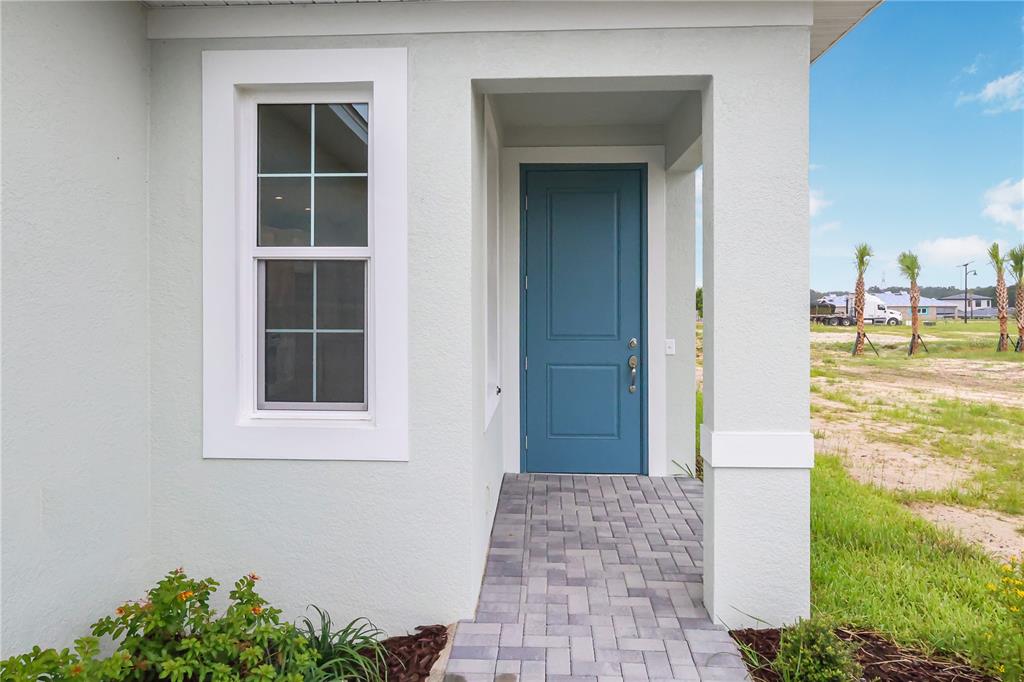 A blue front door and a single window are set into the light-colored exterior wall — 570 HAMMOCK OAKS BOULEVARD, LADY LAKE, FL