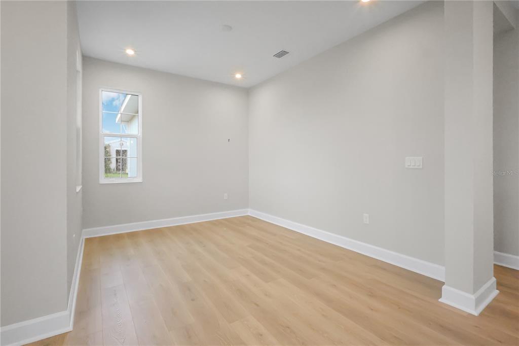 An empty room with light wood-look flooring, gray walls, and a single window — 570 HAMMOCK OAKS BOULEVARD, LADY LAKE, FL