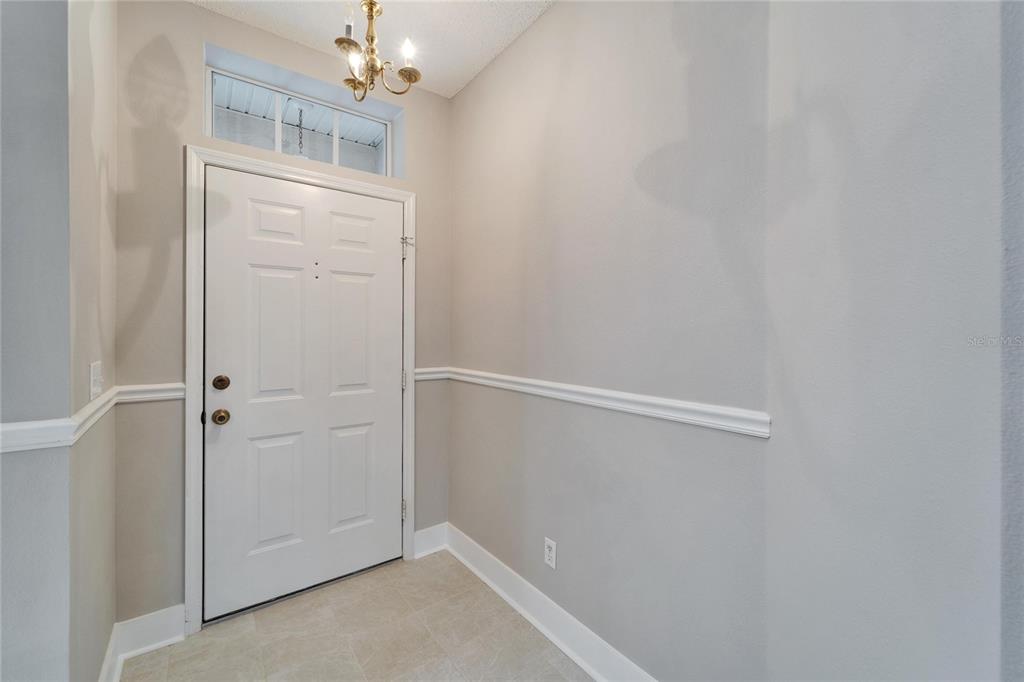 An entryway features a white door, a transom window, a chandelier, and chair rail molding — 1032 RADISON AVENUE UNIT 2, SUN CITY CENTER, FL