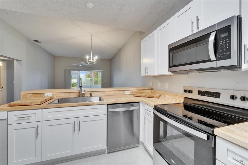 A kitchen features white cabinets, stainless steel appliances, and light wood countertops — 1032 RADISON AVENUE UNIT 2, SUN CITY CENTER, FL