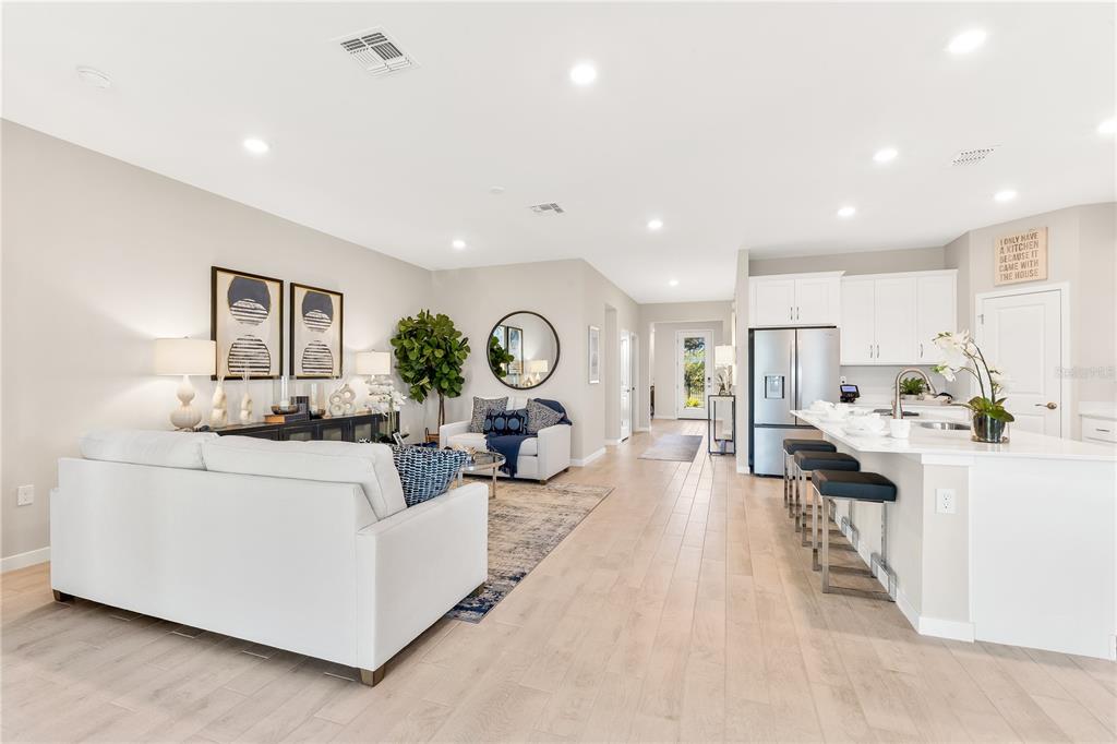 An open-concept living room and kitchen feature light wood floors, white cabinetry, and recessed lighting — 1451 MABLETON DRIVE, PORT CHARLOTTE, FL