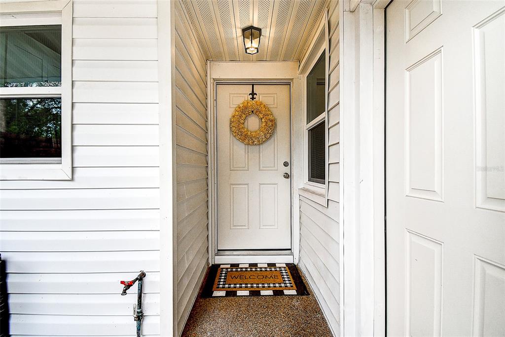 A white front door with a yellow wreath sits in a covered entryway — 1439 WATER VIEW DRIVE W, LARGO, FL