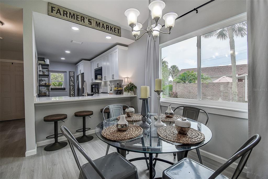 A dining area with a glass table and metal chairs sits beside a kitchen counter — 1439 WATER VIEW DRIVE W, LARGO, FL