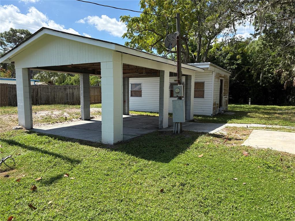 A white carport with concrete pillars stands next to a small, detached white building — 15127 BLUEFISH STREET, HUDSON, FL