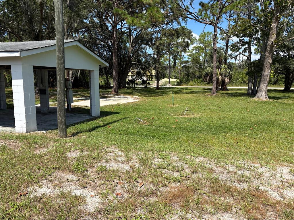 A white open-air pavilion stands on a grassy lot with trees in the background — 15127 BLUEFISH STREET, HUDSON, FL