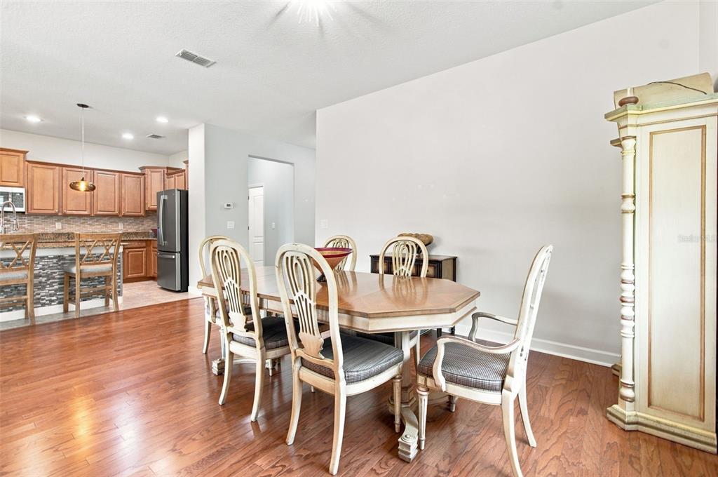 A dining area with a wooden table and chairs sits adjacent to an open kitchen — 20233 MERRY OAK AVENUE, TAMPA, FL