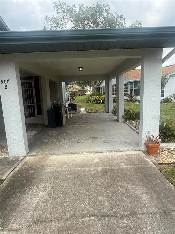 A concrete driveway leads to a covered carport attached to a residential building — 508 FOXGLOVE CIRCLE UNIT B, SUN CITY CENTER, FL