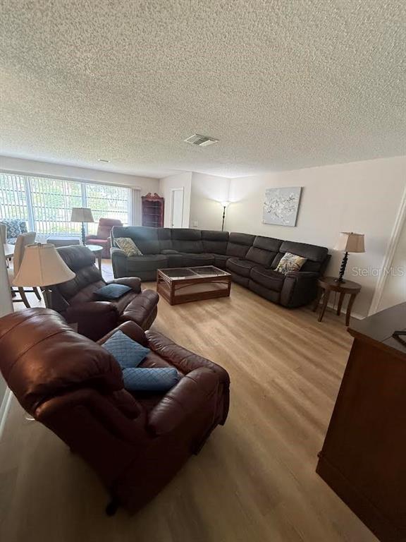 A living room features a large sectional sofa, two leather recliners, and light wood flooring — 508 FOXGLOVE CIRCLE UNIT B, SUN CITY CENTER, FL