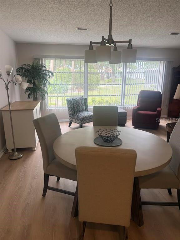 A dining area features a round table with four chairs, a chandelier, and large windows — 508 FOXGLOVE CIRCLE UNIT B, SUN CITY CENTER, FL