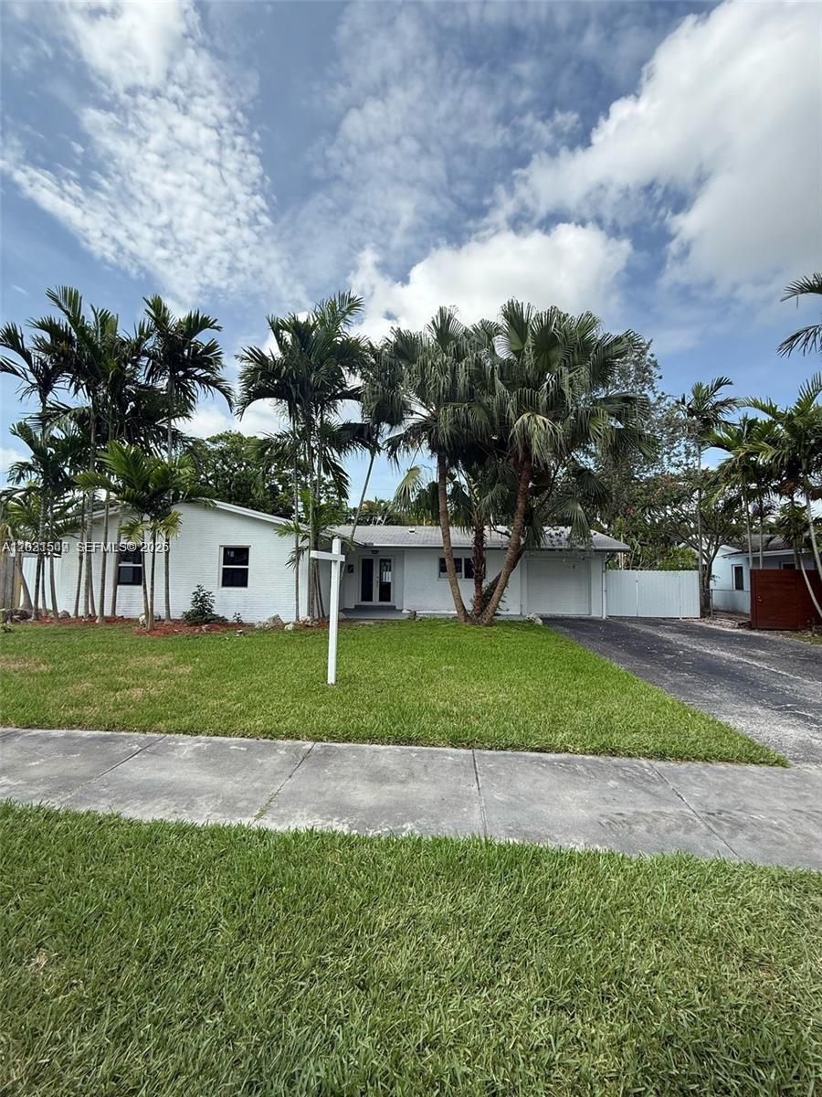 A white, single-story house with a driveway and palm trees sits behind a front lawn — 9934 SW 195th St, Cutler Bay FL 33157, CUTLER BAY, FL