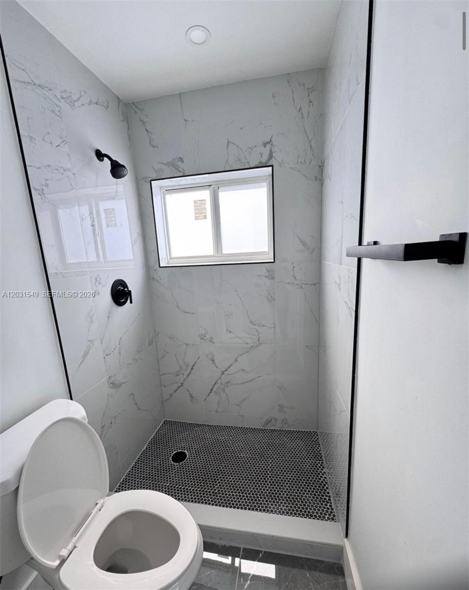 A bathroom features a walk-in shower with marble-patterned tile, black fixtures, and a toilet — 9934 SW 195th St, Cutler Bay FL 33157, CUTLER BAY, FL