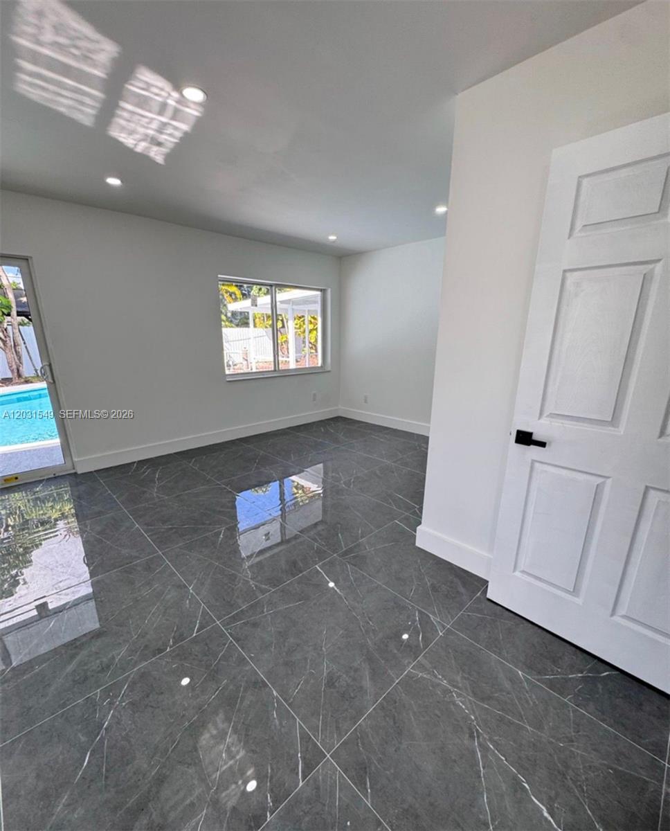 A room with gray marble-look tile flooring, white walls, and a view of a pool — 9934 SW 195th St, Cutler Bay FL 33157, CUTLER BAY, FL