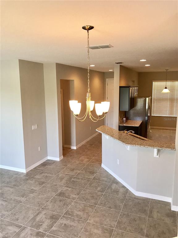 A dining area with a chandelier overlooks a kitchen featuring a granite breakfast bar — 3595 SANCTUARY DRIVE, ST CLOUD, FL