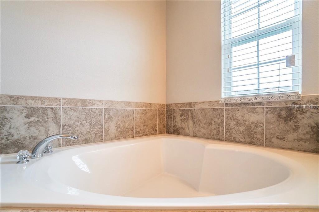 A corner soaking tub features a chrome faucet and a tan tiled backsplash — 3595 SANCTUARY DRIVE, ST CLOUD, FL