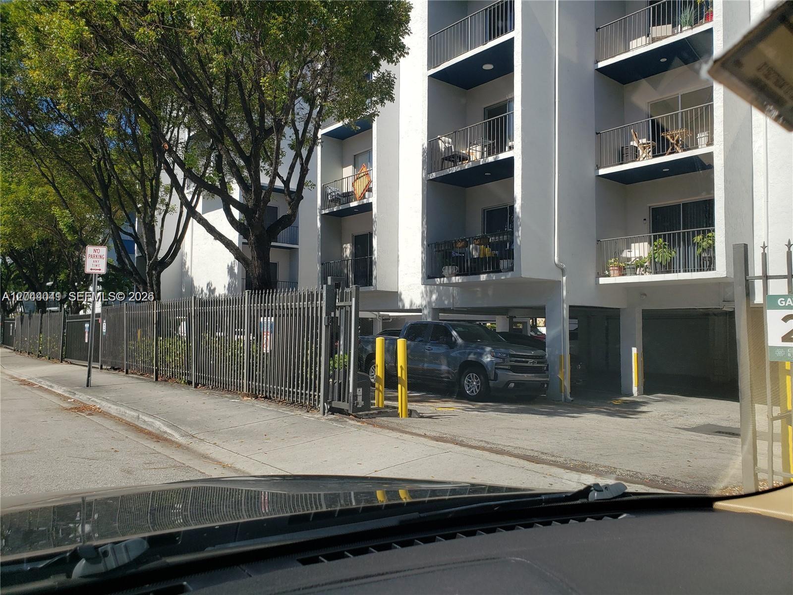 A gray pickup truck is parked under the covered ground floor of a white apartment building — 4550 W 16th Ave # 301, Hialeah FL 33012, HIALEAH, FL