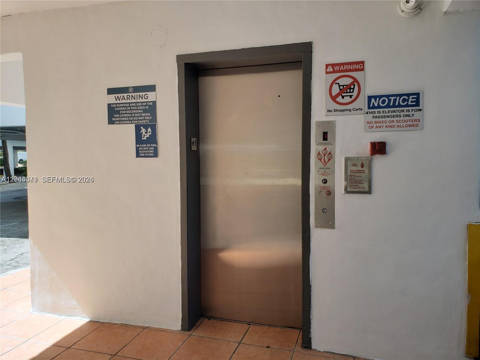 An elevator door is centered on a white wall with various warning and notice signs — 4550 W 16th Ave # 301, Hialeah FL 33012, HIALEAH, FL