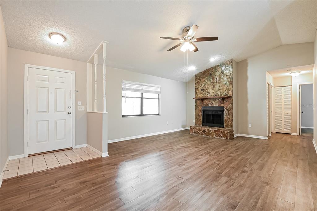 A living room features wood-look flooring, a stone fireplace, and a white front door — 1309 COVE PLACE, TAVARES, FL