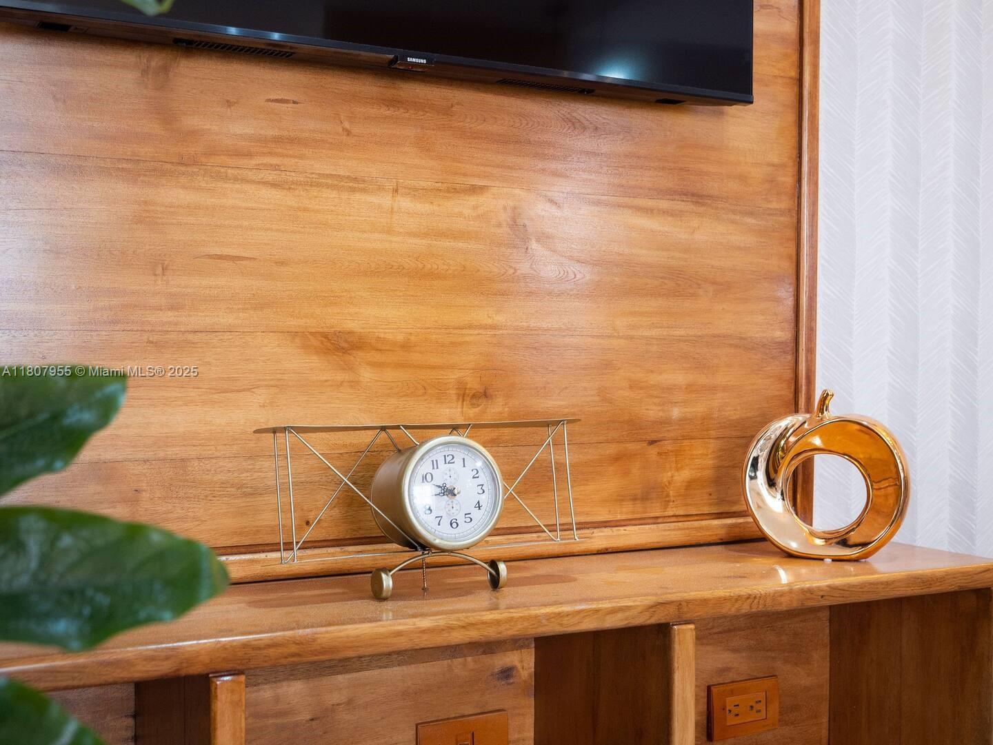 A wooden media console features a decorative airplane clock and a gold sculpture — Julio Aibar #39 Suites By Refa Piantini # 401, RD, RD