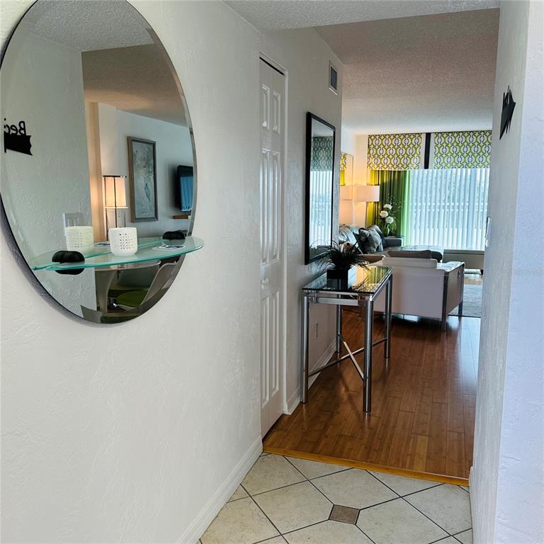 A tiled entryway leads to a living room with hardwood floors and a round mirror — 145 N HALIFAX AVENUE UNIT 405, DAYTONA BEACH, FL