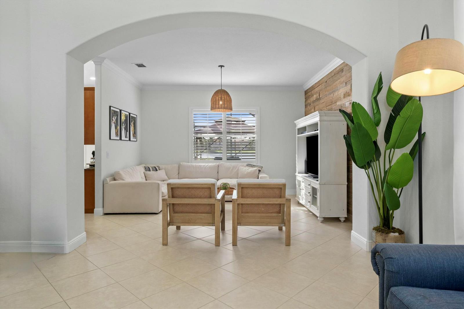 A living room features a sectional sofa, two wooden chairs, and a wood-paneled accent wall — 1386 Beacon Circle, Wellington FL 33414, WELLINGTON, FL