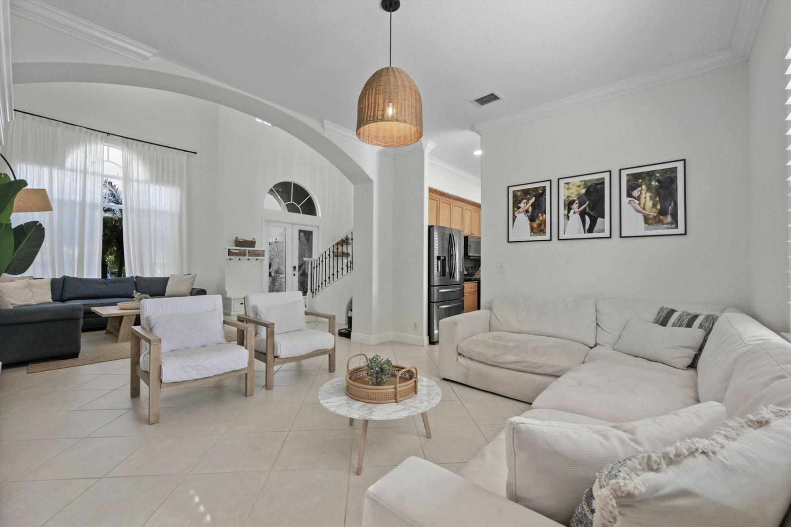 A bright, open-concept living room features white tile floors, a sectional sofa, and arched doorways — 1386 Beacon Circle, Wellington FL 33414, WELLINGTON, FL