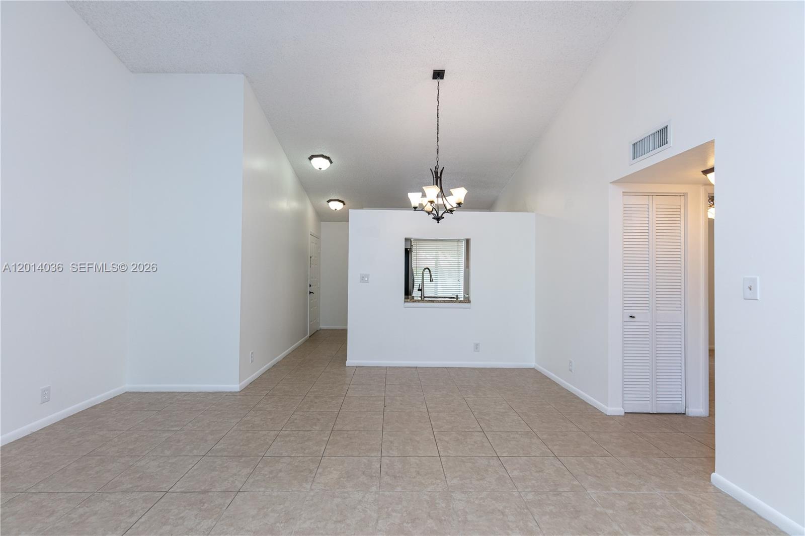 This room features light-colored tile flooring, white walls, a vaulted ceiling, and a kitchen pass-through — 717 Gardens Dr # 201, Pompano Beach FL 33069, POMPANO BEACH, FL