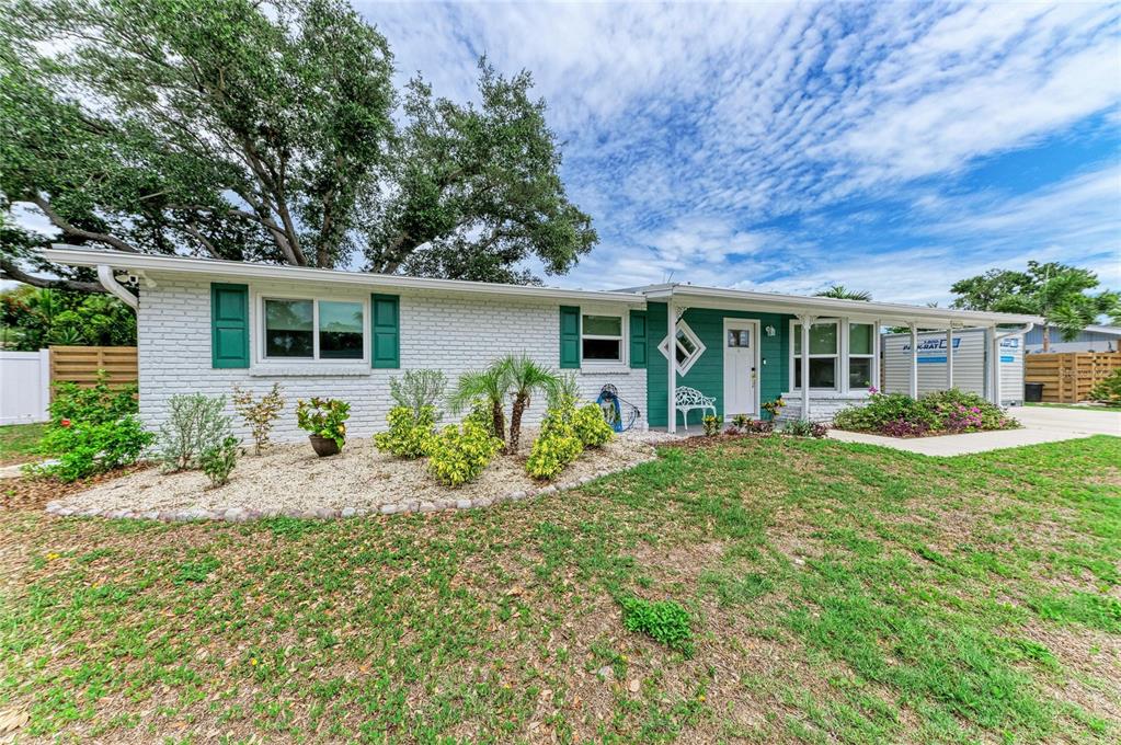 A single-story white brick house with green shutters and a front yard with landscaping — 2317 S TUTTLE AVENUE, SARASOTA, FL