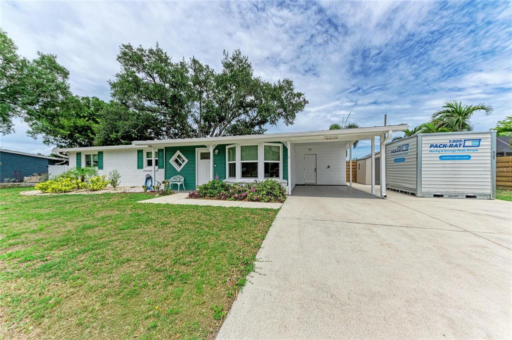 A single-story house with white brick, green siding, a carport, and a storage container — 2317 S TUTTLE AVENUE, SARASOTA, FL