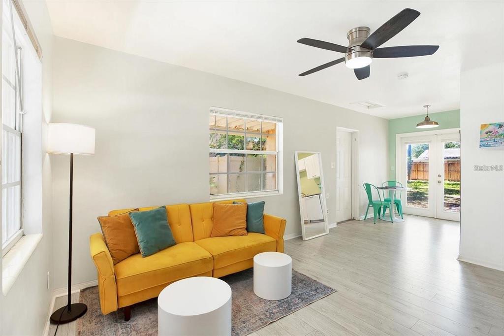 A living room features a yellow sofa, two white stools, and a ceiling fan — 6490 34TH AVENUE N, ST PETERSBURG, FL