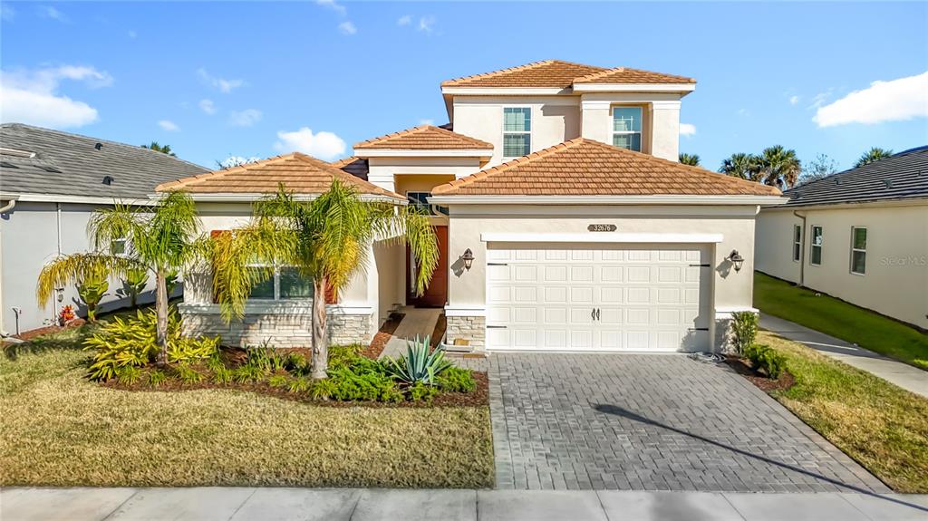 A two-story stucco house with a tiled roof, a paved driveway, and palm trees — 32676 TREE OF LIFE AVENUE, WESLEY CHAPEL, FL
